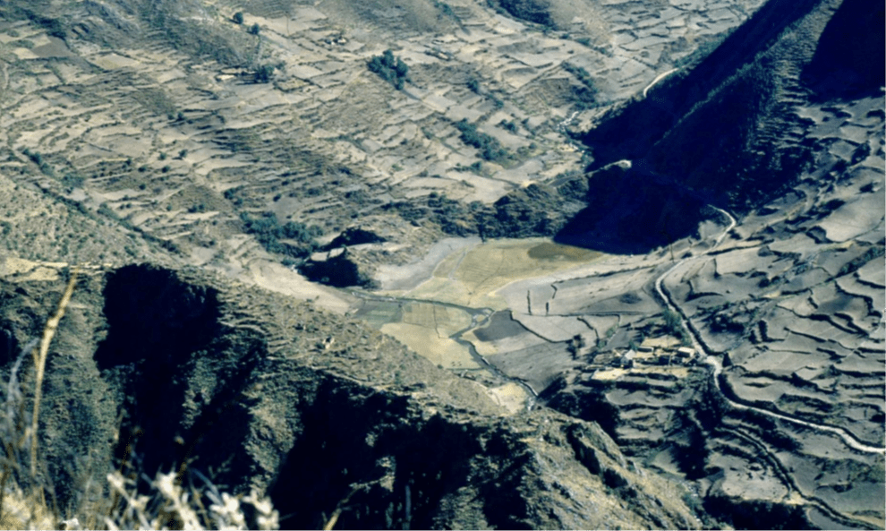 View looking northwards upstream over the Patacancha Valley, with the small infilled lake of Marcacocha (defined by the dark circle of sedge vegetation) set within a landscape of terraces, under-utilised fields and archaeological remains. Photograph taken August 1996 with Marcacocha partly in shadow before 8.30 a.m.